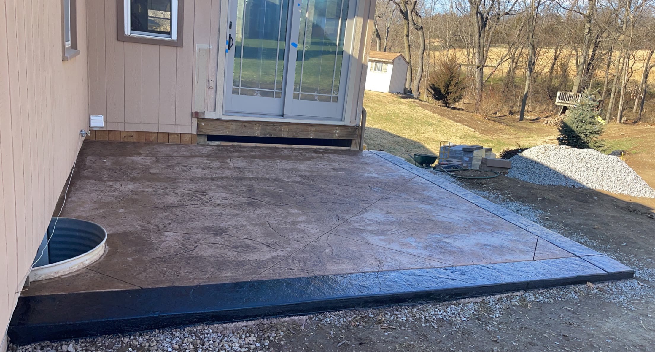 Finished stamped concrete patio with an irregular flagstone pattern in warm tan and brown tones